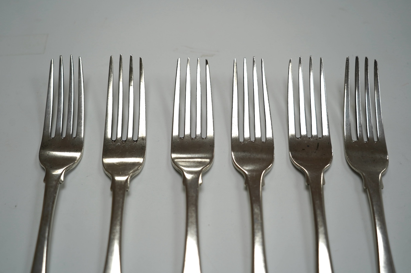 A set of four George III Irish silver fiddle pattern table forks, maker JS, Dublin, 1804, 20.9cm and a similar later pair, 12.8oz. Condition - poor to fair